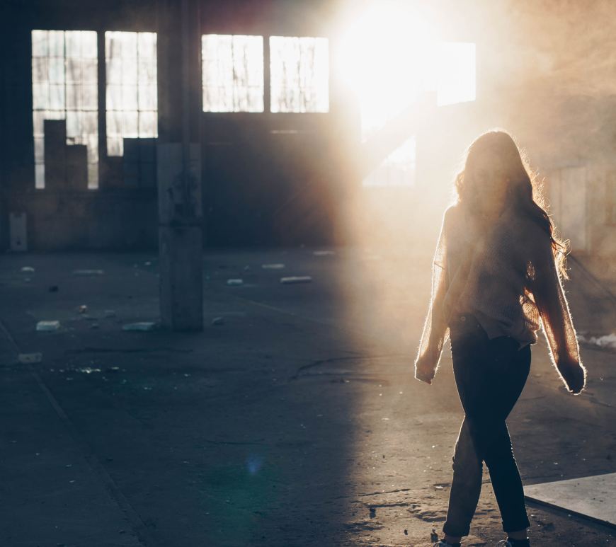 Woman walking with her back to the photo, and the sun shining